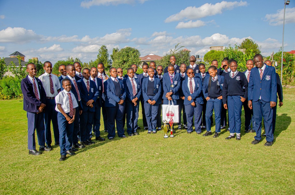 Contest team posing with trophies on the school grounds